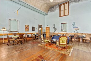 Une pièce spacieuse avec un plancher en bois, un coin repas comprenant des chaises et une table, un canapé et un grand miroir.