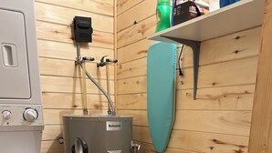 A laundry area with a washing machine, a water heater, and a vacuum cleaner.