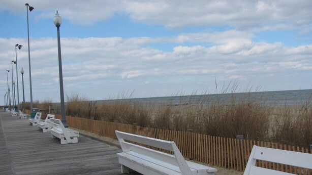 A wooden boardwalk with white benches and street lamps, leading to a beach with sand and tall grasses. - Paradise in Rehoboth.  Beautiful & spacious home -  August dates available. (Rehoboth)