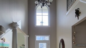 A spacious hallway with a chandelier, a large window, and a staircase. - Paradise in Rehoboth.  Beautiful & spacious home -  August dates available. (Rehoboth)