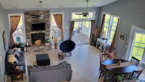 A spacious living room with a stone fireplace, a large TV, and a dining area with a table and chairs. - Paradise in Rehoboth.  Beautiful & spacious home -  August dates available. (Rehoboth)