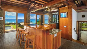 Una cocina con barra, ventanas amplias y vista al océano.