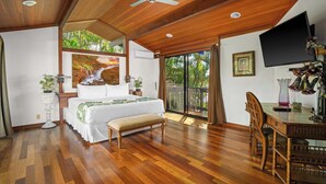 A spacious bedroom with a large bed, a wooden ceiling, and a view of the outdoors.