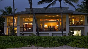 A two-story house with a balcony, large windows, and a well-lit interior. - Hale A Kai By Parrish Kauai: spectacular oceanfront views with private pool & AC (Koloa)