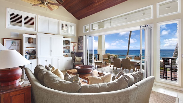 A spacious living room with a large window overlooking the ocean, a cozy seating area, and a wooden ceiling. - Hale A Kai By Parrish Kauai: spectacular oceanfront views with private pool & AC (Koloa)