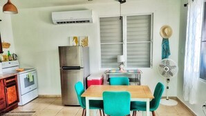 A compact kitchen with a wooden table and teal chairs, a stainless steel refrigerator, and a ceiling fan. - Casa Menta in Rincon, Puerto Rico (Rincon)