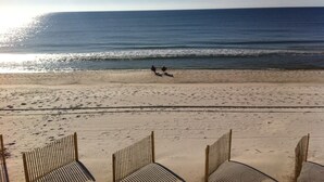 Una platja amb una filera de cadira de platja i una persona corrent al llarg de la riba.