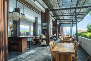 Un restaurante moderno con mesas y sillas de madera, una zona de bar y vistas al mar.
