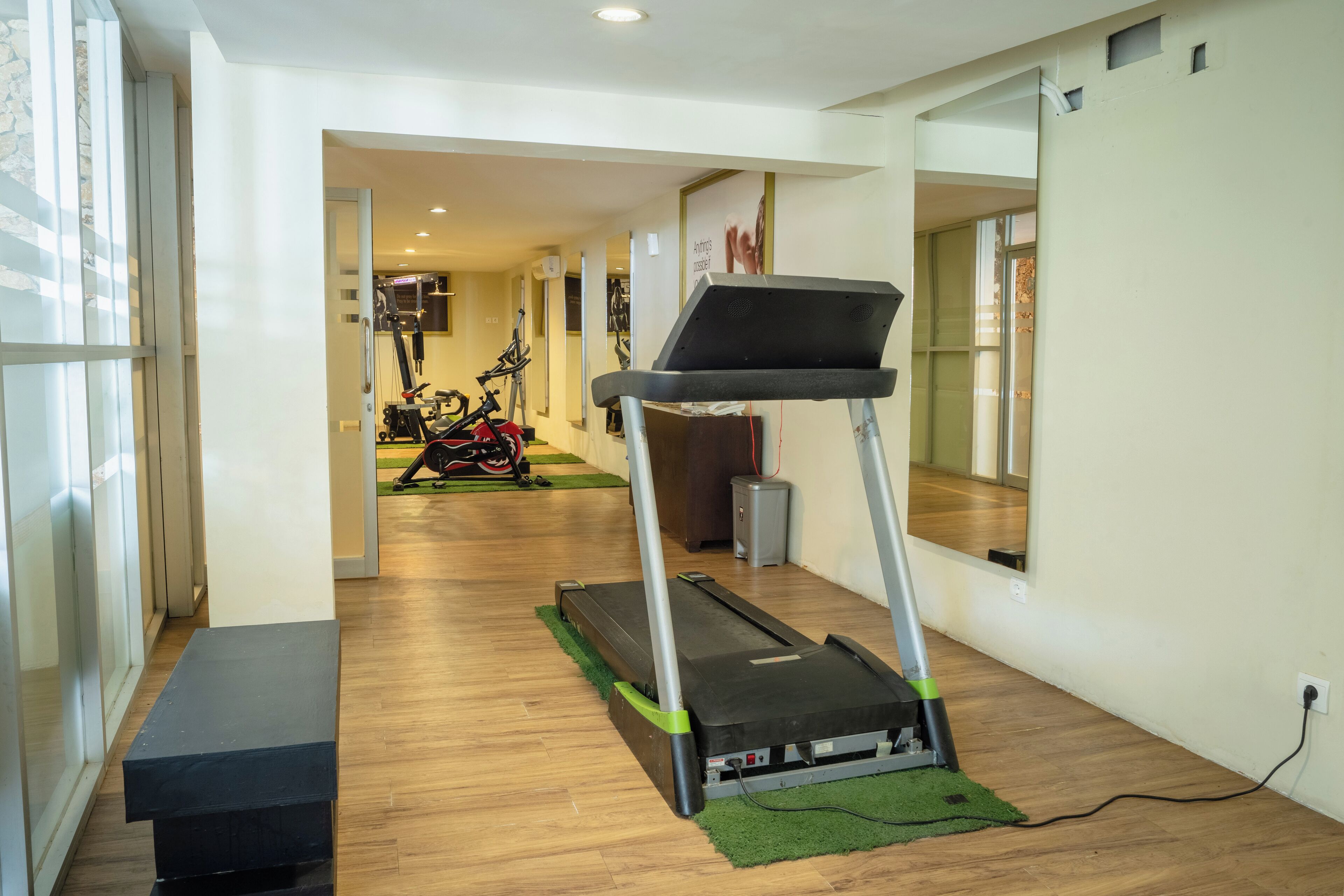 A fitness room with a treadmill, exercise bikes, and a bench.