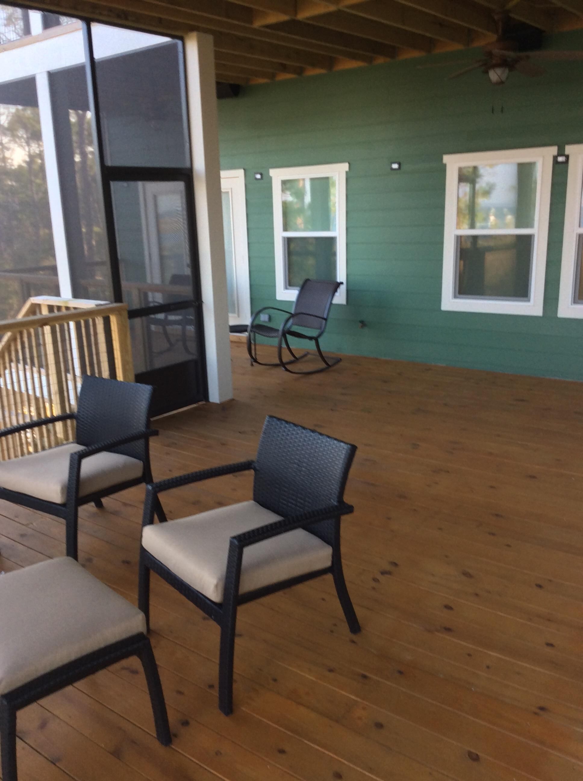 A covered porch with wooden flooring and two rocking chairs.