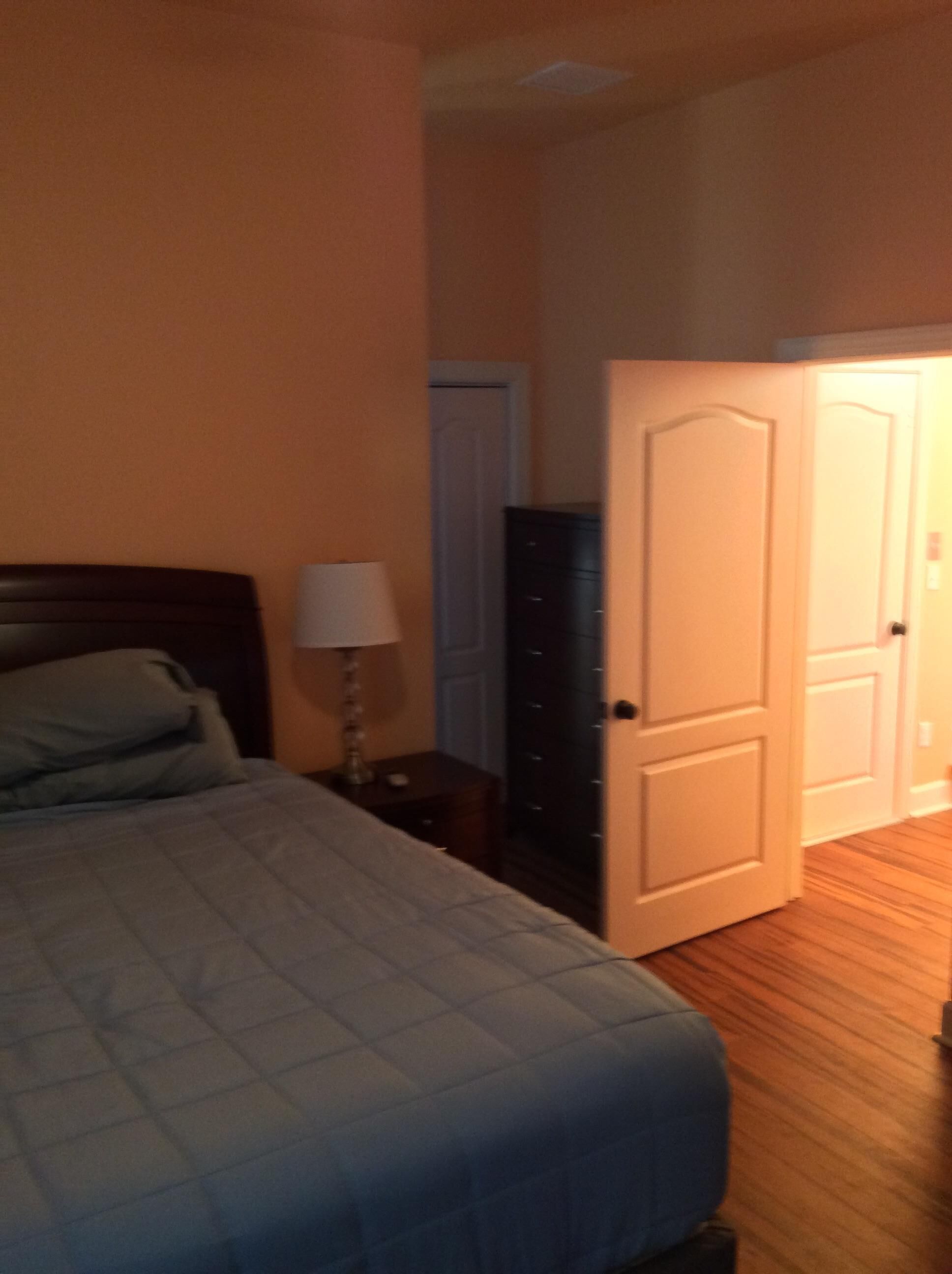 Un dormitorio con cama, mesita de noche, cómoda y una puerta.