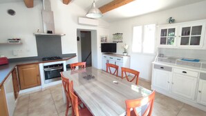 A modern kitchen with a dining table, chairs, and a TV. - La Bastide des Oliviers.charming villa in a peaceful setting with swimming pool
 (callas)
