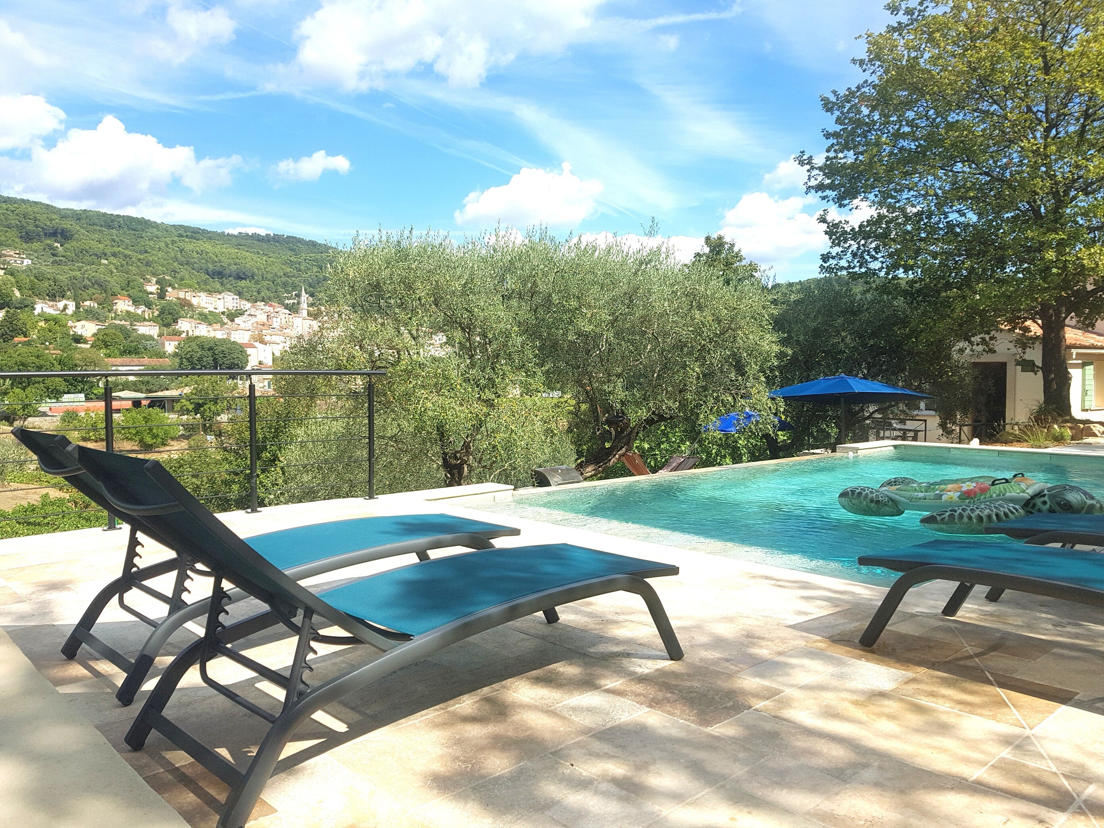 Ein Poolbereich mit Liegestühlen und Blick auf eine Stadt im Hintergrund.