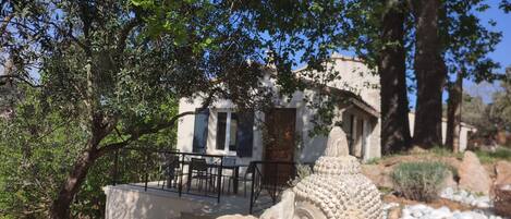 A serene outdoor seating area with a Buddha statue, surrounded by rocks and trees.
