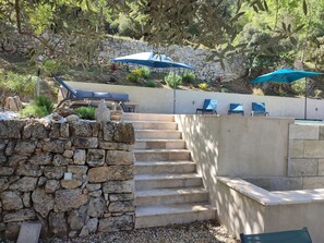 Una escalera de piedra que lleva a un área de descanso con sombrillas azules.