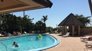 Ein Schwimmbecken mit Liegestühlen und einer Laube.
