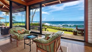 A modern room with large glass windows offering a view of the ocean and a golf course. - Hale Makai By Parrish Kauai- oceanfront with pool and AC, honeymoon haven at Hal (Koloa)