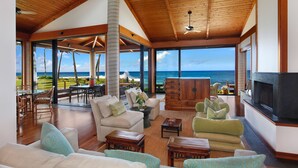 A spacious living room with a large TV, comfortable seating, and a view of the ocean. - Hale Makai By Parrish Kauai- oceanfront with pool and AC, honeymoon haven at Hal (Koloa)