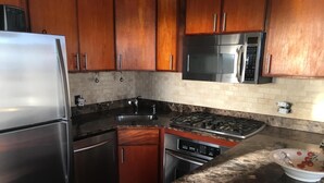 A kitchen with wooden cabinets, stainless steel appliances, a granite countertop, and a white tiled backsplash. - SPECTACULAR OCEAN VIEW VILLA BLISS AT UPPER DECK WITH GENERATOR (St John)