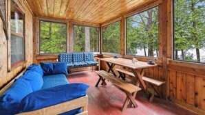 Eine Holzhütte mit einer Couch, einer Bank und einem Picknicktisch.