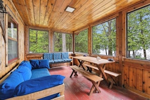A wooden cabin with a sofa, bench, and picnic table.
