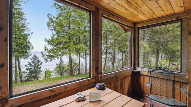 Eine Holzdiele mit großen Fenstern mit Blick auf einen See und Wald.
