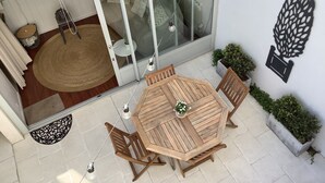 Ein Holz-Tisch- und Stuhlgarnitur auf einer Terrasse mit einer Glastür zu einem Innenraum.