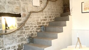 Eine Treppe mit Steinwänden, ein weißer Tisch mit Stühlen und ein gerahmtes Bild an der Wand.