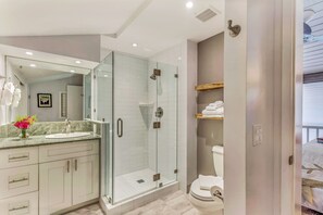 A modern bathroom with a glass-enclosed shower, a large mirror, and a vanity with a marble countertop. - Gorgeous Updated Oceanfront Condo 2BR /2BA AMAZING Molokai Views~Hale Honu (Lahaina)