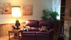 A cozy living room with a leather sofa, a small side table, a lamp, a fireplace, and a large fur rug. - Rim Country Living in the heart of Arizona (Payson)