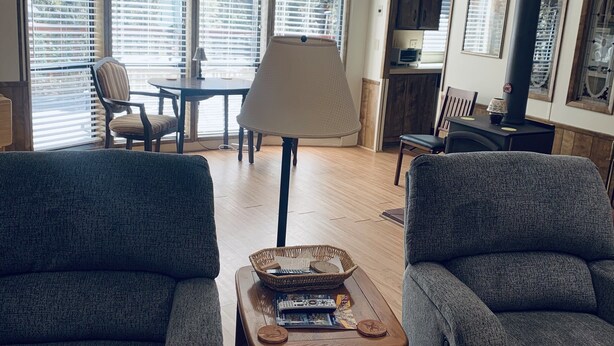 A living room with two grey armchairs, a wooden coffee table with books and a basket, a lamp, and a fireplace. - Rim Country Living in the heart of Arizona (Payson)