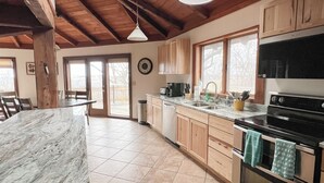 A kitchen with wooden cabinets, a marble countertop, a sink, a stove, and a clock on the wall. - Beautiful compound, 10 mile views, on 300 acre ranch, next to Galena Territory (Elizabeth)