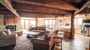 A spacious living area with a fireplace, a sofa, a coffee table, and a dining area with a kitchen in the background. - Beautiful compound, 10 mile views, on 300 acre ranch, next to Galena Territory (Elizabeth)