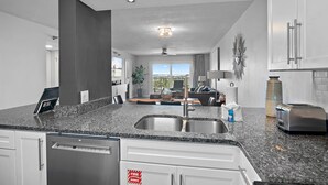 A modern kitchen with granite countertops, stainless steel appliances, and a large window offering a view of the outdoors. - PARADISE + Incredible Views! Platinum Plus Escape – Islander 514 (Destin)