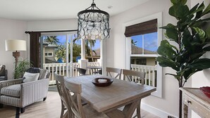 Un espace repas avec une table et des chaises en bois, un lustre et une vue sur l’extérieur.