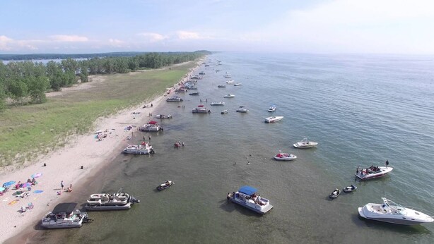 A beach with numerous boats anchored in the water and people on the shore. - Cozy cottage in Sandy Pond (Pulaski)