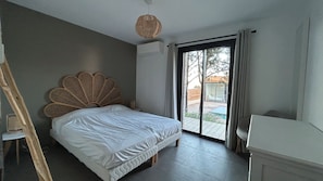 A bedroom with a bed, a wicker headboard, a sliding glass door, and a small bedside table. - Villa breathtaking sea view with pool, 550m from the beach, for 14 people (Serra-Di-Ferro)