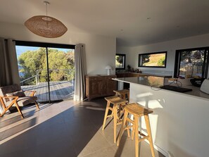 A modern kitchen with a large island, bar stools, and a view of the outdoors. - Villa breathtaking sea view with pool, 550m from the beach, for 14 people (Serra-Di-Ferro)