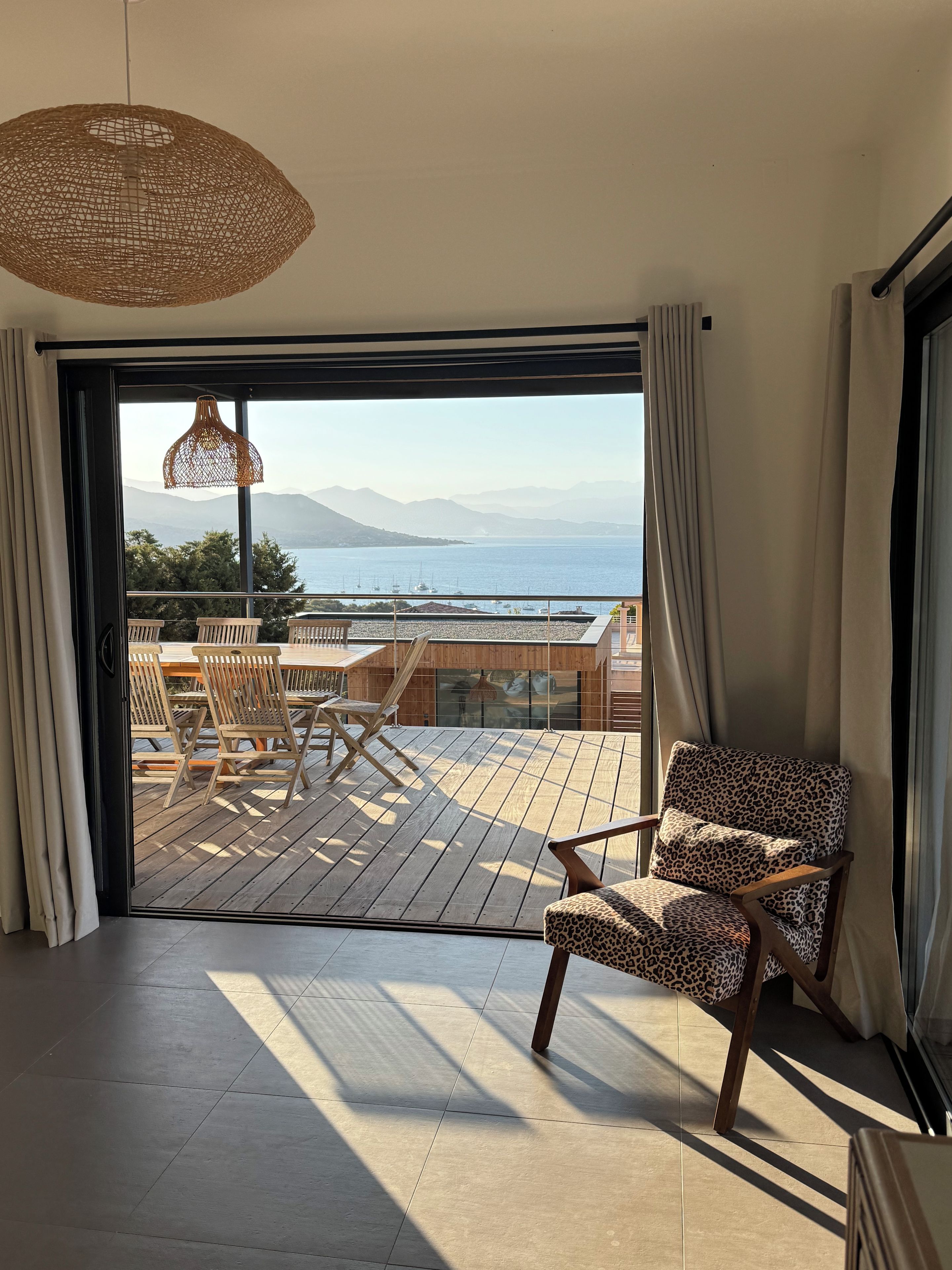 Una stanza con vista sul mare, un pontile di legno con sedie e un lampadario.
