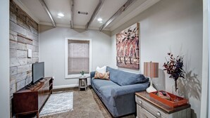 A cozy living room with a sofa, TV, and decorative items. - Charming One-Bedroom Unit in Historic Belhaven! (Jackson)