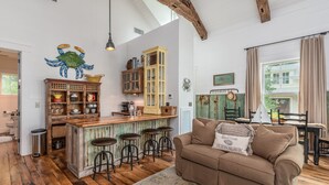 A rustic kitchen with wooden bar stools, a wooden island, and a green door. - Cedar Bluff Cabin in May in Old Town Bluffton on the river (Bluffton)