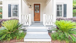 A white house with a wooden front door, two white railings, and a small porch. - Cedar Bluff Cabin in May in Old Town Bluffton on the river (Bluffton)
