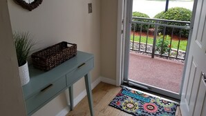 A room with a light blue console table, a wicker basket, a potted plant, and a colorful welcome mat. - Beautiful Ponce Inlet 2bd Condo.  100 Yards to the Beach! Beach supplies/bikes.  (Ponce Inlet)