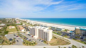 A coastal hotel with a parking lot, a beach view, and a large building with multiple floors. - Beautiful Ponce Inlet 2bd Condo.  100 Yards to the Beach! Beach supplies/bikes.  (Ponce Inlet)