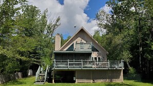 A two-story house with a balcony, surrounded by trees and a fenced yard. - Peace and quiet on the lake (Becket)