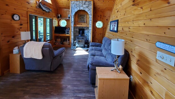 A cozy cabin interior with a stone fireplace, wooden walls, and a comfortable seating area. - Peace and quiet on the lake (Becket)