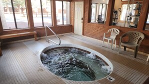 Ein Whirlpool in einem Raum mit Fliesenboden, einer Bank und zwei Stühlen.