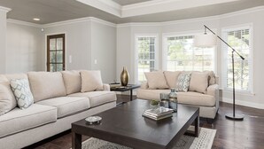 Una sala de estar con dos sofás color beige, una mesa de centro de madera oscura y una lámpara de pie.