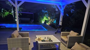 An outdoor patio with wicker furniture, a pool, and a grill.