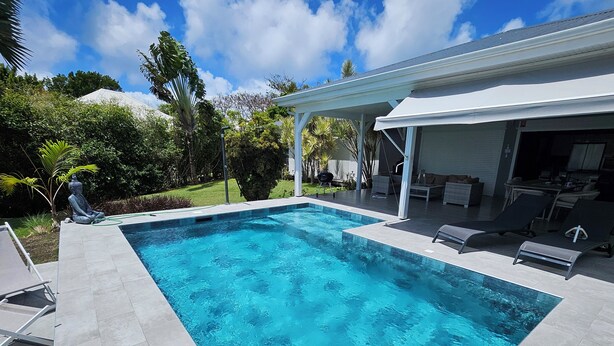 A rectangular swimming pool with clear blue water, surrounded by a tiled deck.